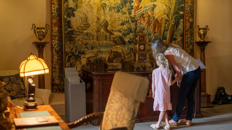 Visitors examine a tapestry inside the house at Anglesey Abbey Cambridgeshire